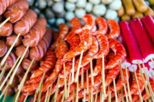 Stacked skewers of hot dogs, shrimp, and other meats